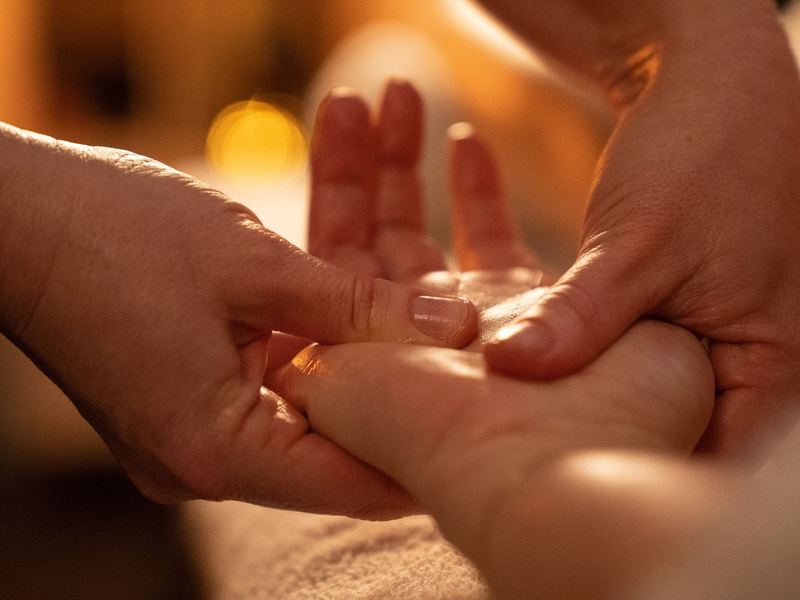 Twee handen masseren traag en aandachtig een hand
