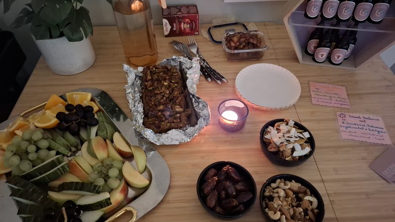 Een gedeelde tafel met fruit, dadels, noten, cake en een theelichtje